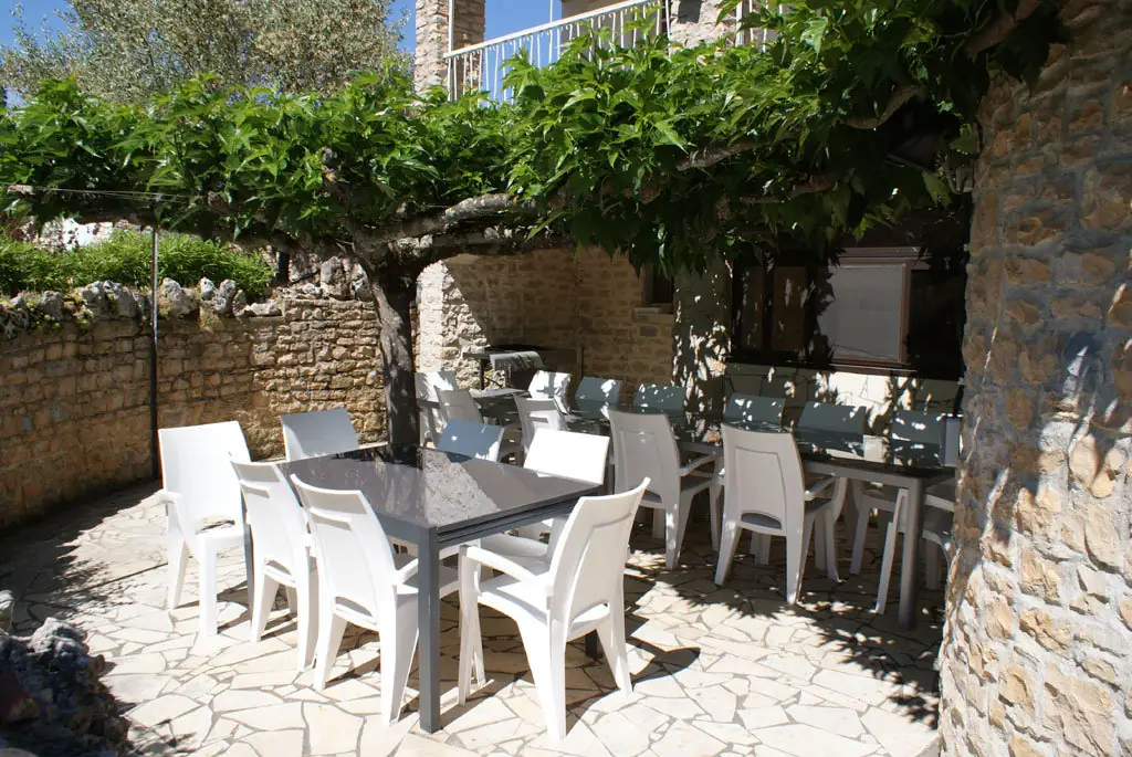 Shaded terrace under the pergola, with tables and chairs