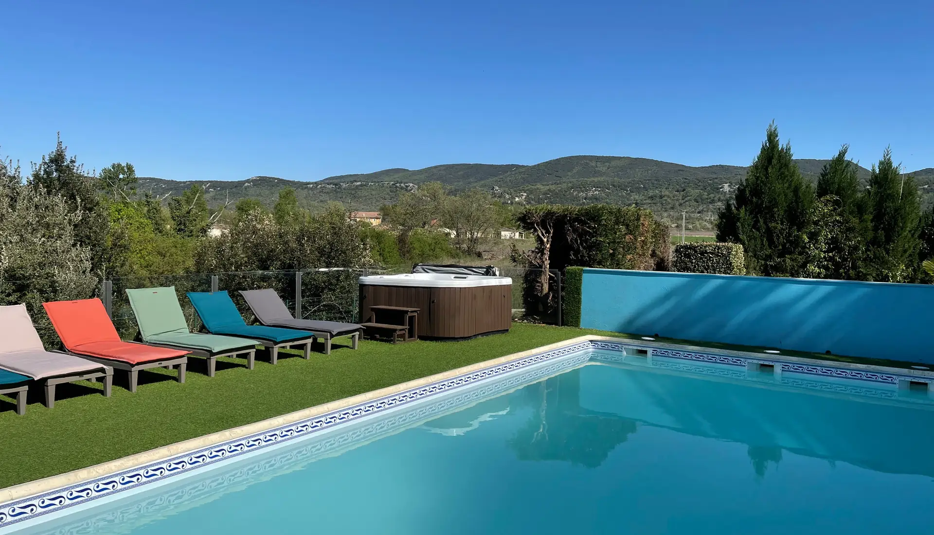 Heated pool lined with colourful sun loungers and lawn